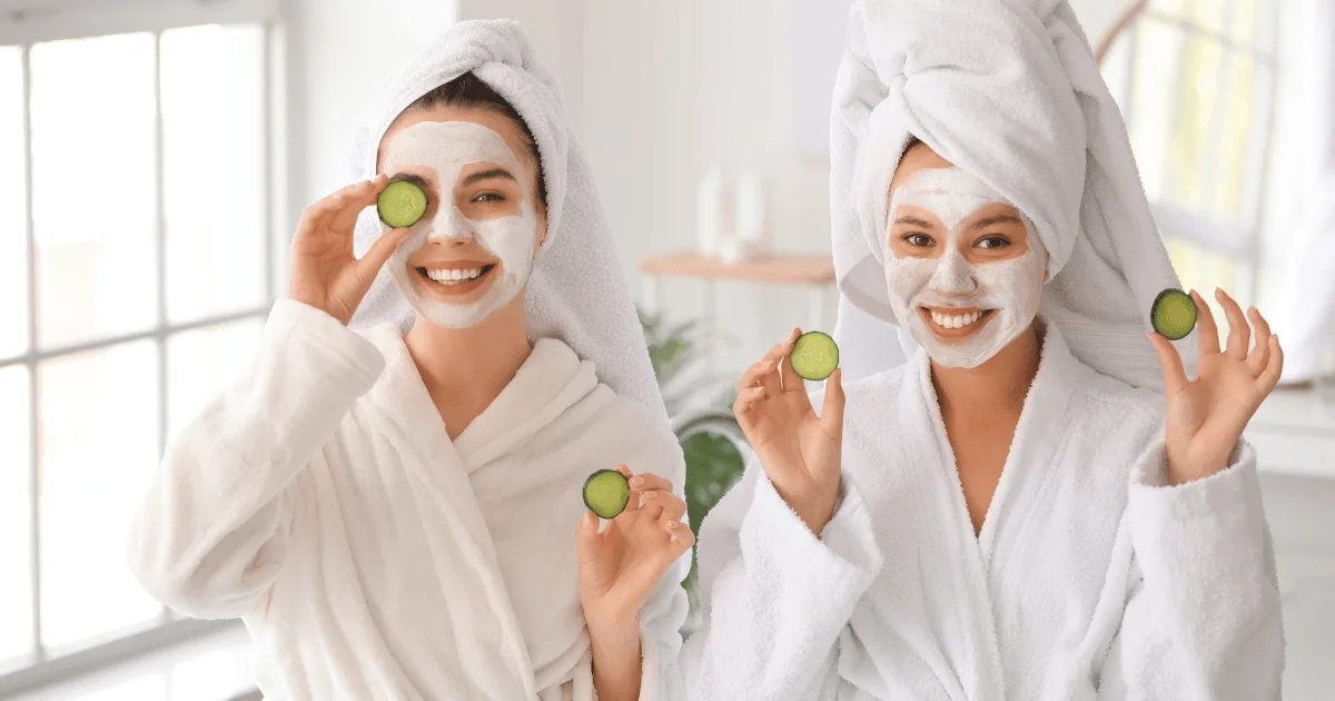 Two woman with clay face mask on holding Cucumbers