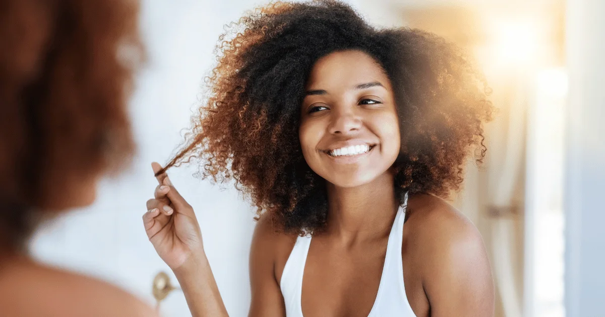 A woman looking at her hair through the mirror